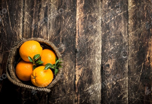 Preview: Fresh oranges in a wooden bucket.