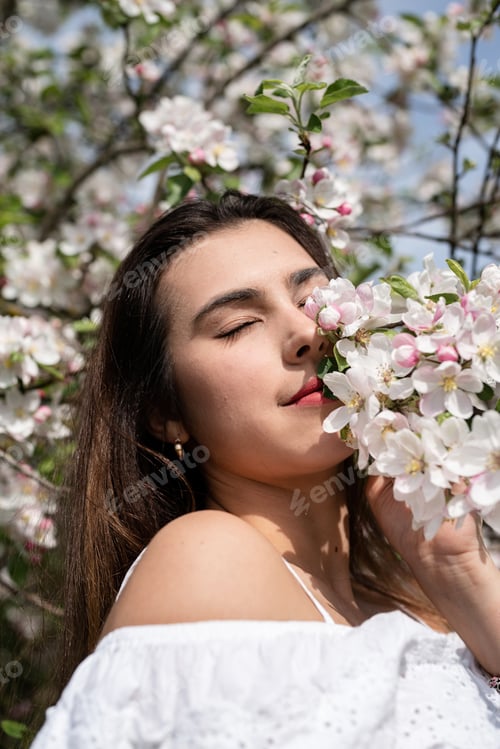 Preview: Young caucasian woman enjoying the flowering of an apple trees