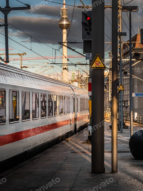 Preview: Vertical shot of a white train with a red line at a train station at sunset