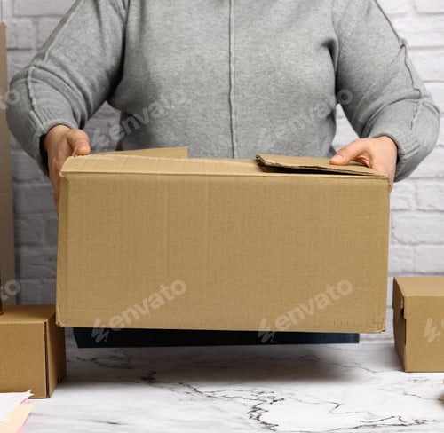 Preview: Woman in a gray sweater holding a brown cardboard box