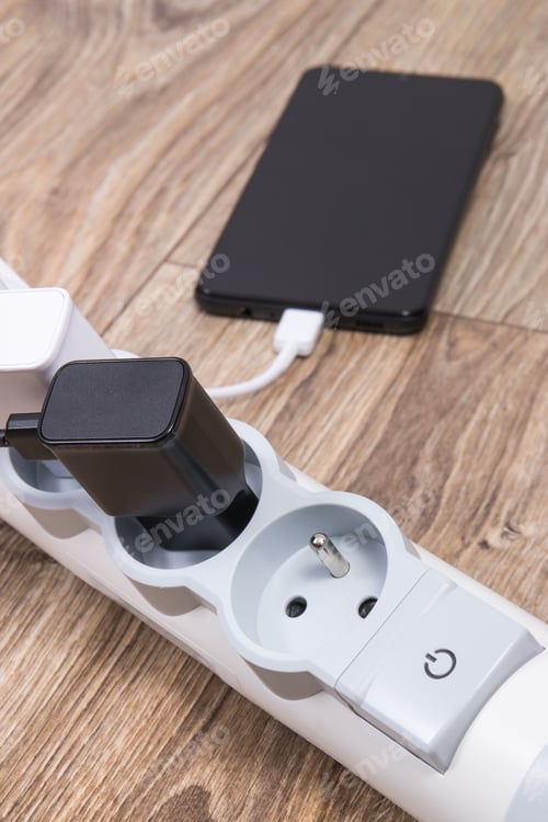 Preview: Smartphone and chargers connected to electrical power strip. Various devices charging concept