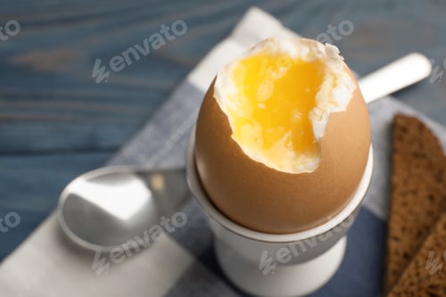 Preview: Holder with soft boiled egg on table, closeup. Space for text