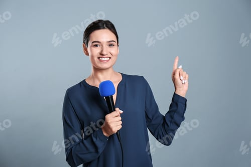 Preview: Young female journalist with microphone on grey background