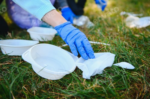 Preview: hand puts plastic debris in the garbage bag in the park