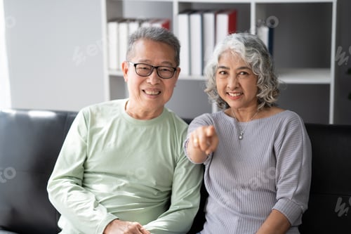 Preview: A happy senior couple sitting on a sofa indoors, spend their quality time together, showing love and