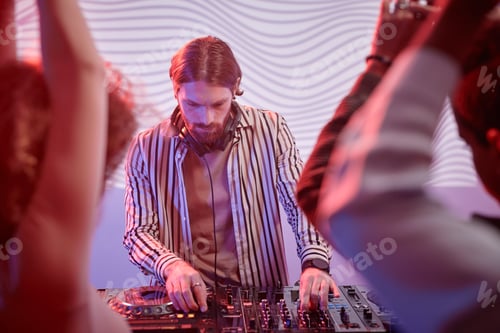 Preview: DJ by turntable in neon lights with dancing crowd in nightclub