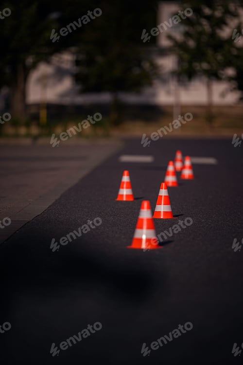 Preview: Orange Traffic Cones Aligned on Asphalt Road in Sunlight