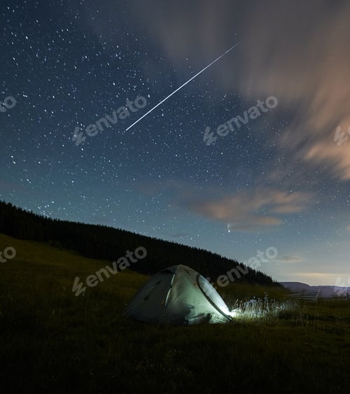 Preview: Blue tent near forest under starry sky.