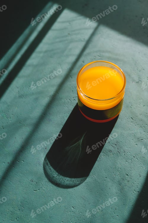 Preview: Summer creative photography with sunlight and shadows of orange juice.