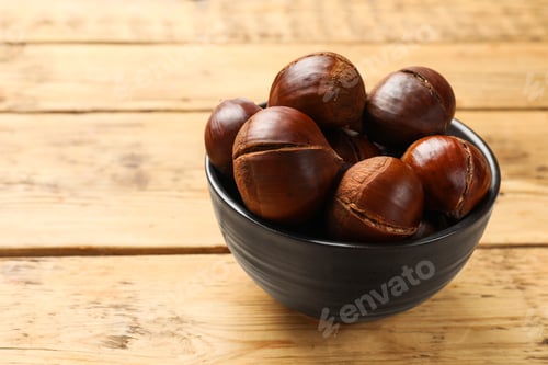 Preview: Fresh edible sweet chestnuts in bowl on wooden table. Space for text