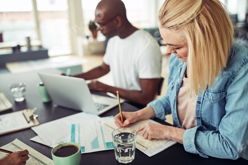 Preview: Smiling young businesswoman working with colleagues at an office table