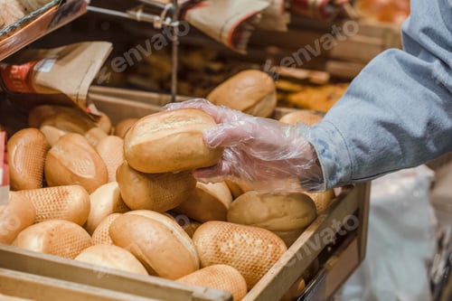 Preview: A young woman takes from the counter in the supermarket fresh bread .