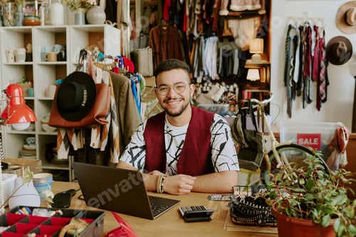 Preview: Smiling Man Sitting in Boutique Among Clothing Displays