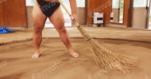 Preview: Broom, dohyo and legs of Sumo wrestler sweeping sand in mawashi, getting ready for competition. Cl