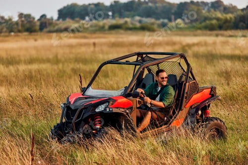 Preview: A smiling man driving a rented quad bike and looking around the nature.