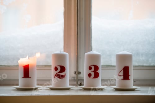 Preview: Four advent candles on a windowsill with the first candle lit to celebrate the season