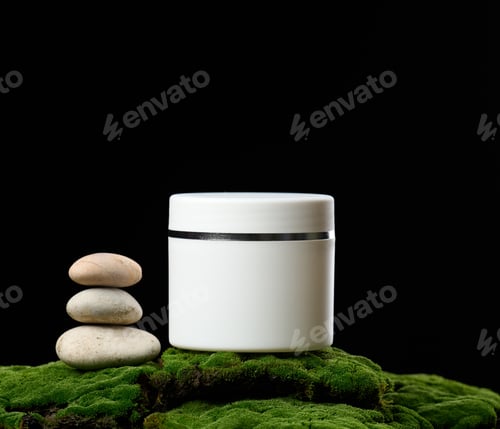 Preview: Round white plastic jar with lid for cosmetics stands on green moss, black background