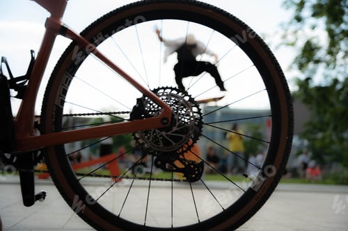 Preview: Male skateboarder jumps over a street seen from a bicycle tire.