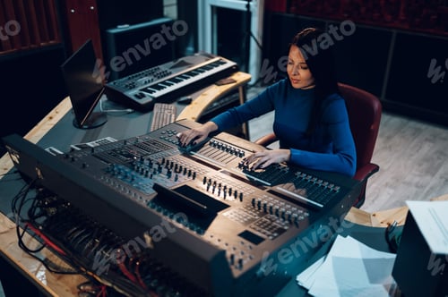Preview: Woman music producer working on a mixing soundboard in a studio.