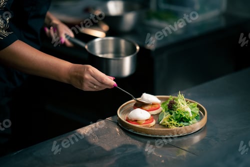 Preview: in a professional kitchen on clean metal table a woman chef collects a salad with fresh meat and