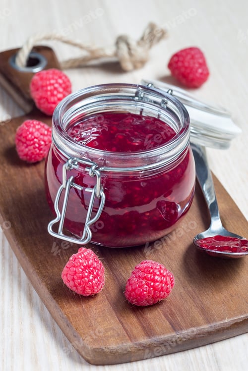 Preview: Raspberry jam in glass jar on wooden board, vertical
