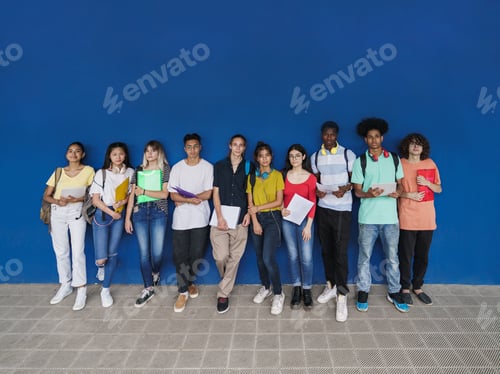 Preview: multiracial teenager students looking to camera standing over blue wall copy space