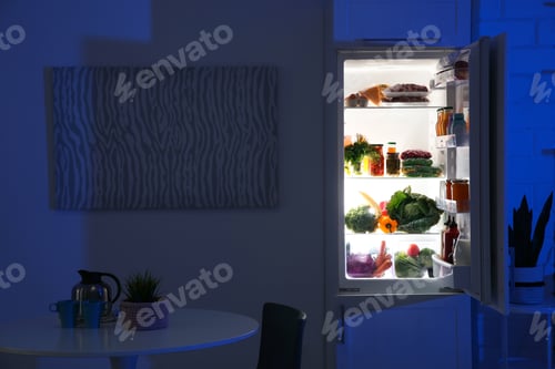 Preview: Stylish kitchen interior with refrigerator full of products at night
