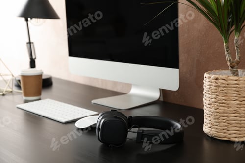 Preview: Workplace with computer and plant on wooden table. Light brown background