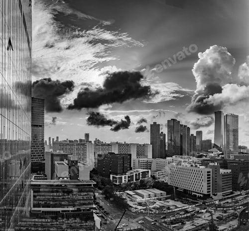 Preview: Grayscale shot of a modern city skyline under dark cloudy sky