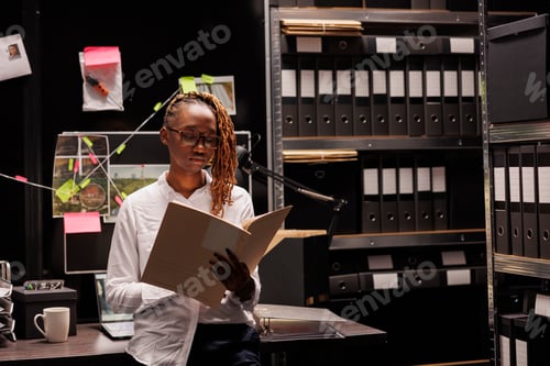 Preview: Serious african american woman detective studying crime matter file