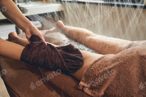 Preview: Female lying on the wooden desk while having shower rain and massage on legs