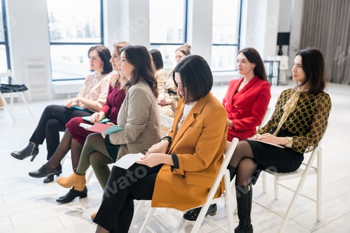 Preview: Side view of females sitting in the audience for business training. Women outlining coach speech