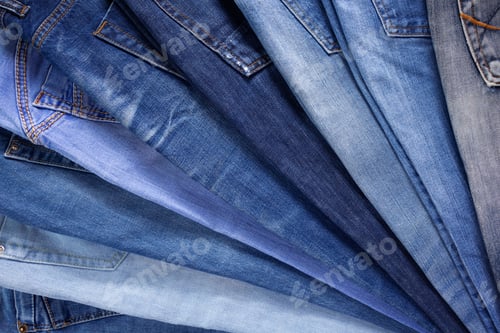 Preview: Blue jeans denim heap background. Jeans fabric stack as material surface