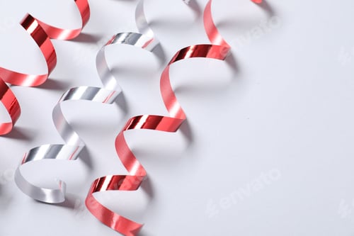 Preview: Shiny serpentine streamers on white background, above view. Space for text