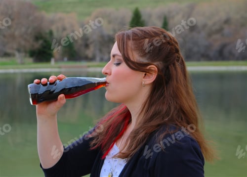 Preview: Young woman enjoys a cold beverage at the lake