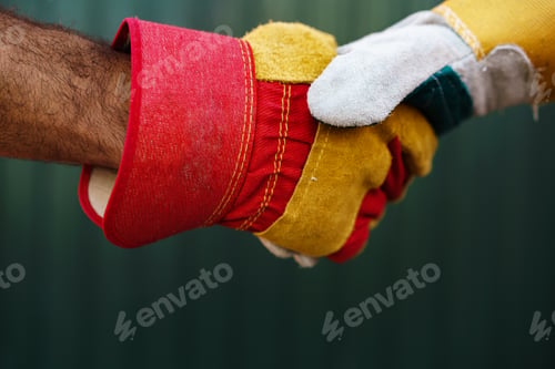 Preview: Close up photo of two men builders in workwear shaking hands
