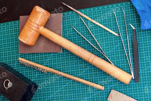Preview: Overhead view on jewelcrafting tools on a green cutting mat.