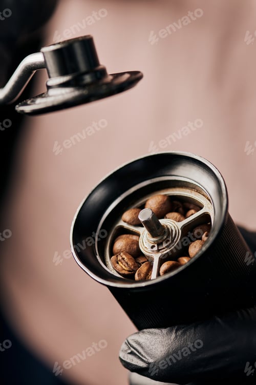 Preview: cropped view of barista holding manual coffee grinder with coffee beans, arabica, close up, energy