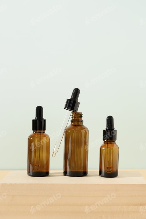 Preview: Natural essential or serum oil in dark glass bottle on a wooden stand on beige background.