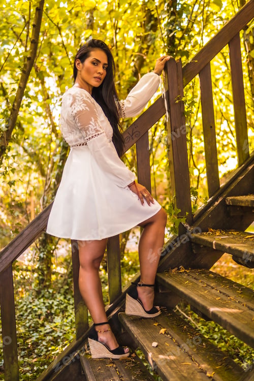 Preview: Lifestyle, brunette girl with straight hair in a beautiful white dress in a park