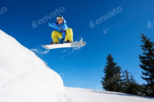 Vorschau: Springender Snowboarder hält eine Hand auf dem Snowboard auf blauem Himmelshintergrund