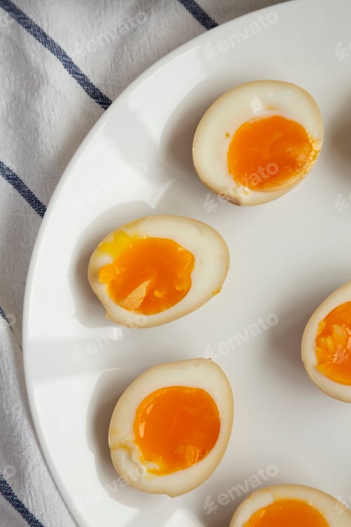Preview: Homemade Unami Soy Sauce Eggs on a white plate, top view. Close-up.