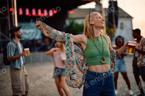 Preview: Carefree woman having fun and dancing while attending open air music festival in summer.