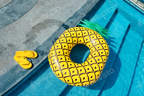 Preview: Yellow sandals and swim rings at the pool on a hot summer day