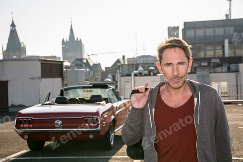 Preview: Germany, Cologne, portrait of mature man in front of his parked sports car on parking level