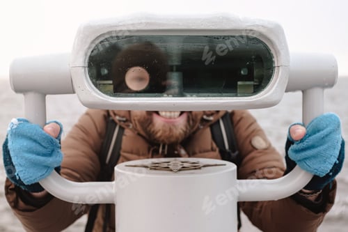 Preview: Cheerful man with funny face expression looks at tower viewer like a robot, against the sea