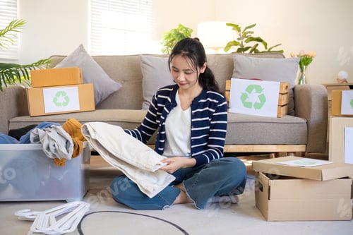Preview: A young woman separates unused clothes and prepares them for donation or recycling in order to