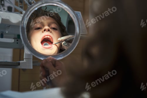 Preview: Dentist checking boy using mouth mirror in office