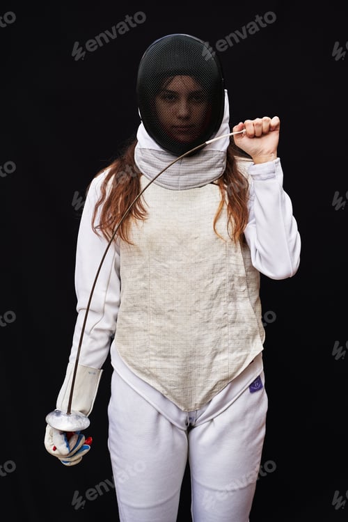 Preview: Portrait of woman dressed in fencing costume on black background.