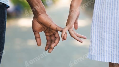 Preview: Loving couple holding little fingers while walking